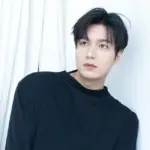 Retrato do ator sul-coreano Lee Min-ho vestindo um suéter preto de gola redonda, olhando pensativamente para o lado, adequado para uma biografia.