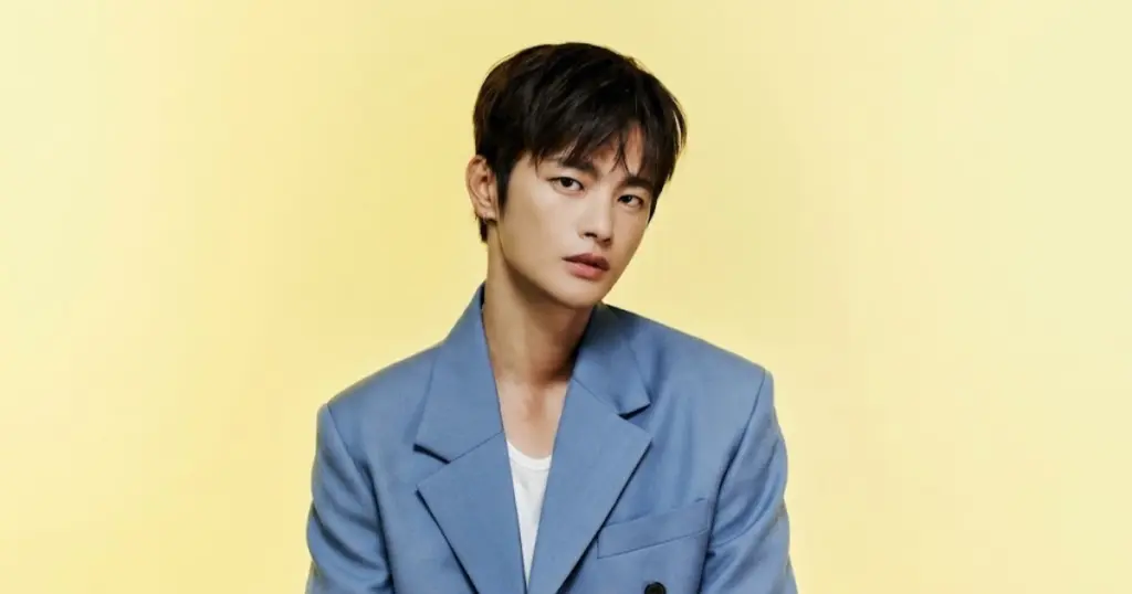 Retrato do ator e cantor sul-coreano Seo In-guk vestindo um terno azul claro de estilo elegante em um fundo amarelo.